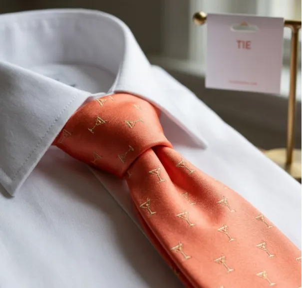 Close-up of patterned coral-orange necktie with a 'Tie' brand tag.